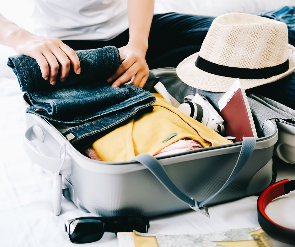 An open suitcase with a person place jeans inside.